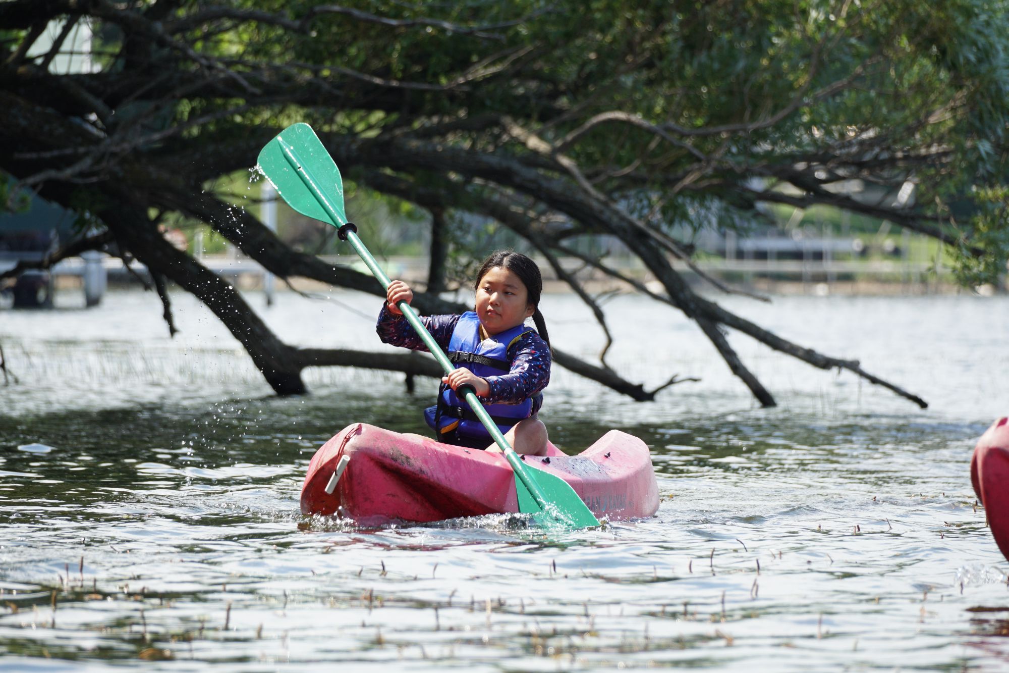 A child paddles a kayak on a lake